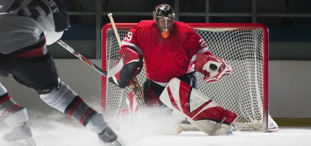 Player shooting the puck against a goalie making a glove save